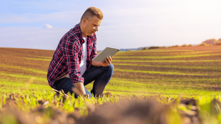 Agricultor utilizando tablet em plantação, representando investimentos em inovação no agronegócio gaúcho.