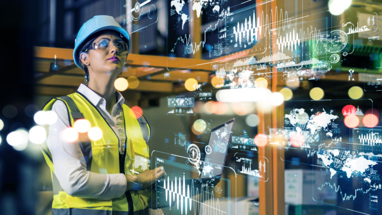 Engenheira da indústria utilizando laptop em ambiente tecnológico com gráficos digitais, simbolizando otimismo do setor industrial com a economia.