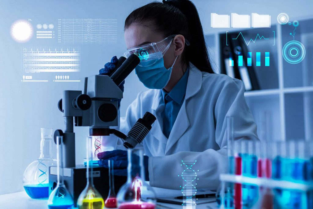 Pesquisadora em laboratório usando microscópio com painéis digitais, representando pesquisa em ciências ambientais e cooperação FAPESP–NERC.