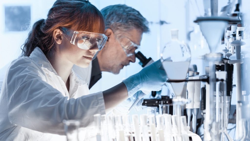 Pesquisadores em laboratório usando pipeta e microscópio, representando o aporte da FAPESP de R$ 800 milhões para ciência e pesquisa no Brasil.