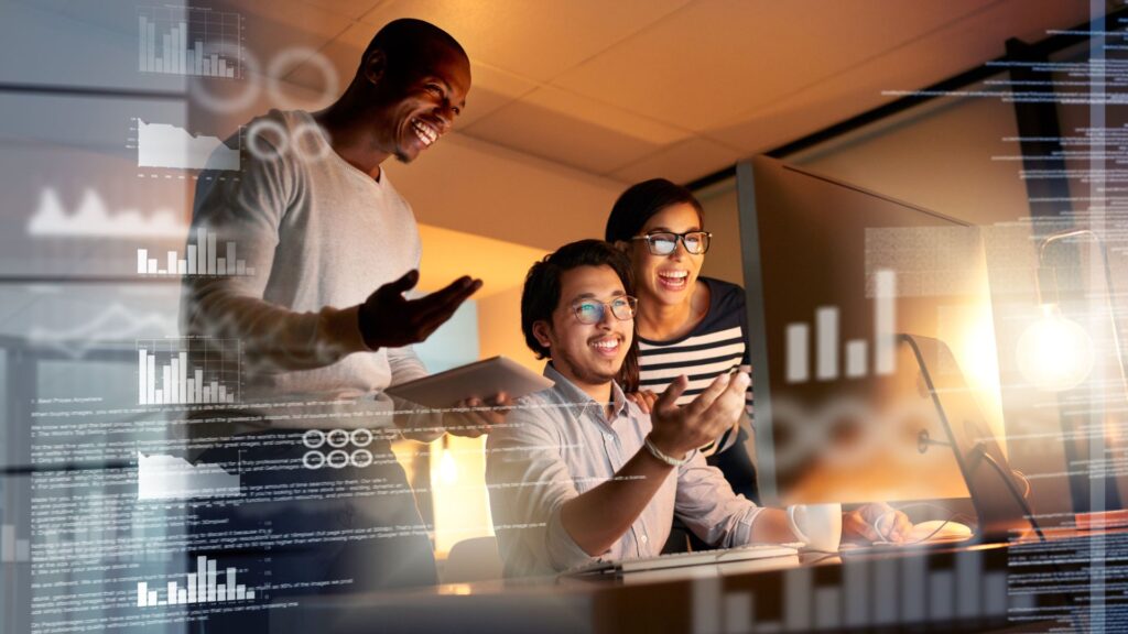 Equipe comemora diante de computador com dashboards digitais — Brasil se une à Rede Eureka para impulsionar inovação, P&D e cooperação internacional.