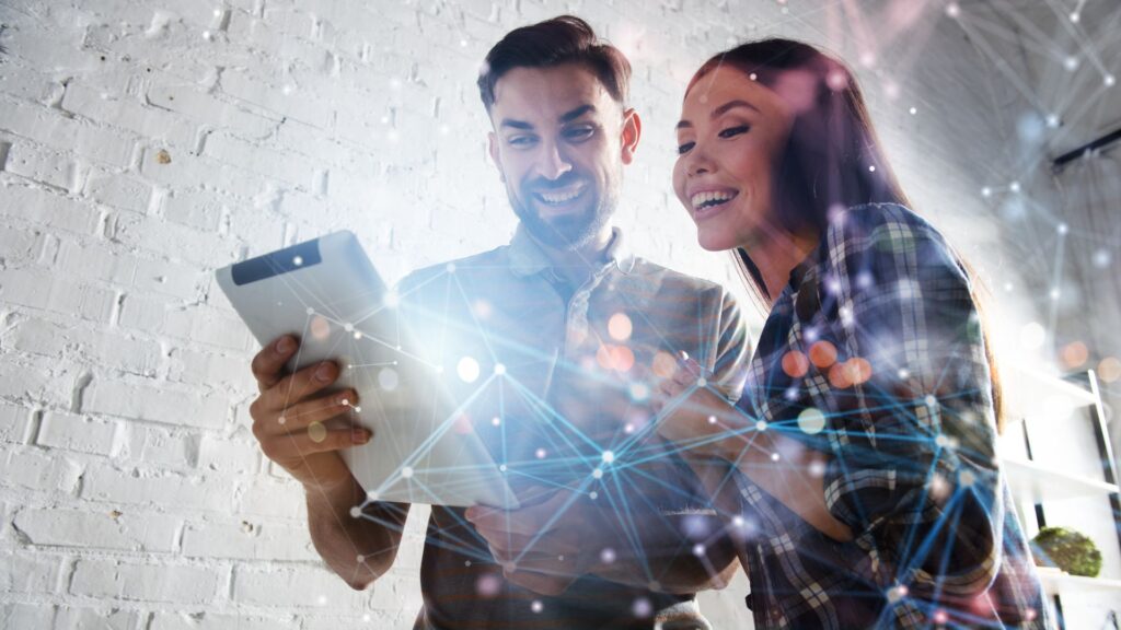 Empreendedores analisam tablet com interface digital — BNDES reduz valor mínimo para financiar projetos de inovação no Norte e Nordeste.