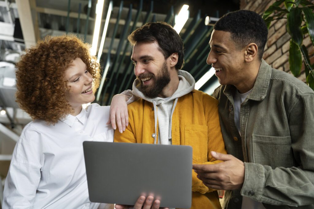 Três jovens empreendedores em coworking olhando um notebook — ecossistema de startups de ciência e tecnologia em São Paulo.