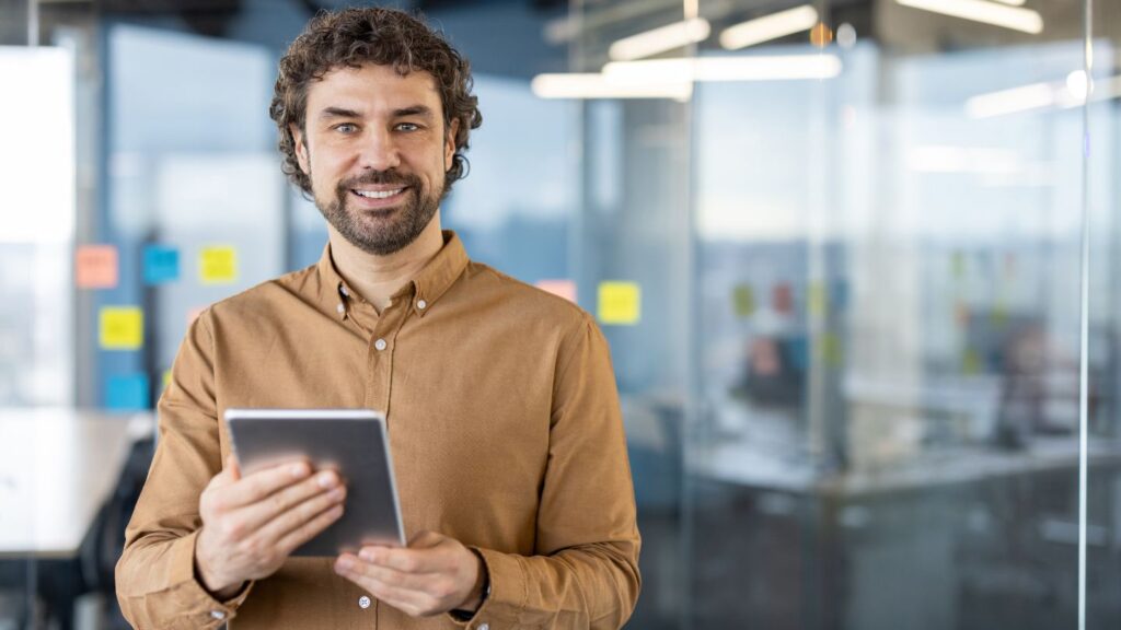 Gestor segura um tablet em escritório com post-its, conduzindo a gestão estratégica da inovação do diagnóstico à implementação.