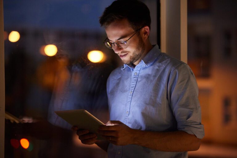 Profissional consulta tablet à noite, simbolizando modelo operacional para inovação.