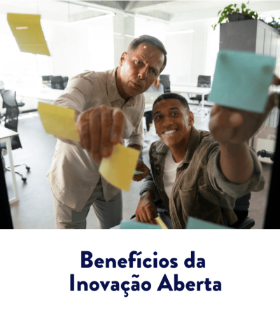 Dois colegas colam post-its em um painel de vidro no escritório, colaborando e sorrindo — benefícios da inovação aberta.